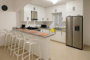 a kitchen with a counter with stools and a refrigerator at Spacious Home with Private Pool in San Felipe de Puerto Plata