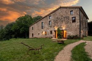 an old stone house with a bench in front of it at Mas Casalprim in Sant Feliu de Pallerols