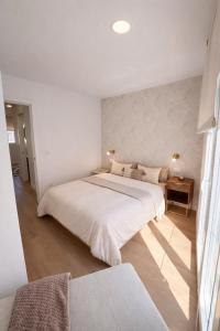 a white bedroom with a large bed and a table at Casa Cuca O Grove in O Grove