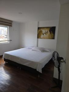 a bedroom with a bed with a painting on the wall at Lindo apto cerca a todo! in Sabaneta