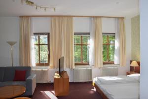 a bedroom with a bed and a couch and windows at Hotel Liszt in Weimar