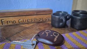 a key on a table next to some cups at Emo Guesthouse in Kpandu