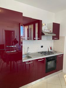 a kitchen with red cabinets and a sink and a stove at Appartamento Gardenia in Saronno