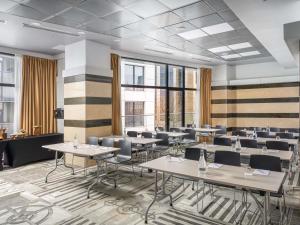 a dining room with tables and chairs and windows at Mercure Bucharest Unirii in Bucharest