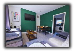 a living room with a green wall and a table at Pitchside Quarters Near Anfield sleeps 7 in Liverpool