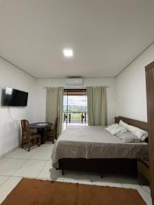 a bedroom with a bed and a table and a television at Chácara Vittorino in Artur Nogueira +22 photos
