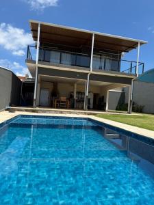a house with a swimming pool in front of a house at Chácara Vittorino in Artur Nogueira