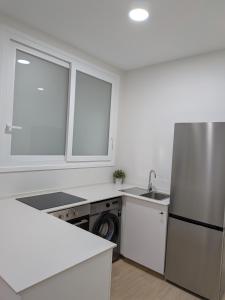 a white kitchen with a refrigerator and a dishwasher at Apartamento Calle Bolsa in Sanlúcar de Barrameda +1 photo