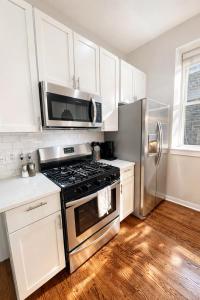a kitchen with a stove and a stainless steel refrigerator at Flexhome West Town - Spacious 2BR Duplex - Sleeps 8 in Chicago