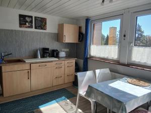 a kitchen with a table and a sink and two windows at Landhotel Eisdorf in Eisdorf