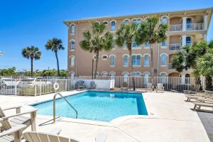 a swimming pool in front of a building with palm trees at Tranquillity 140 - A Wave From It All in Inlet Beach