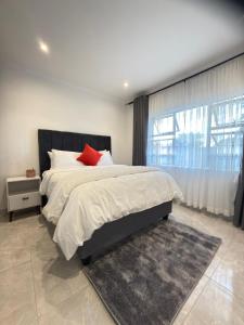 a bedroom with a large bed with a red pillow at Palmview in Bulawayo