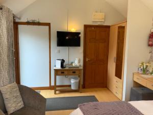 a room with a bed and a desk with a television at Whortleberry Studio B & B in Porlock