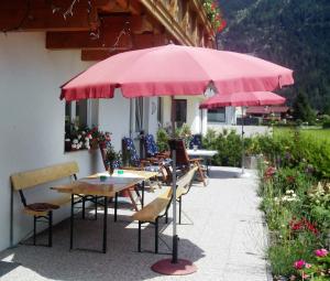 a group of tables and chairs under a pink umbrella at Appartment Christine in Längenfeld