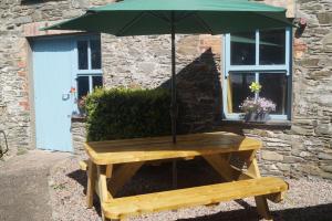 a wooden bench with an umbrella in front of a building at The Narrows Guesthouse in Portaferry