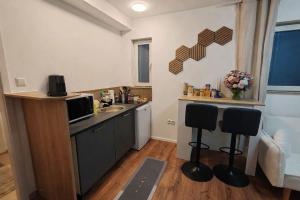 a kitchen with a sink and a counter with two stools at Basel Access Apart - Habsheim in Habsheim