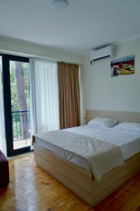 a bedroom with a large bed and a large window at Ferre Hotel Shekvetili in Natanebis Sadguri