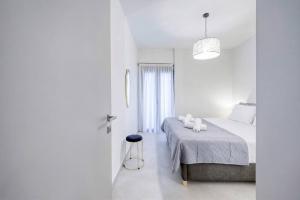 a white bedroom with a bed and a stool at Alba Luxury Suite Trikala in Tríkala