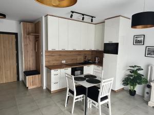 a kitchen with white cabinets and a table and chairs at Czarno biały in Racibórz