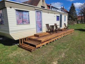 a mobile home with a deck with chairs and a table at Mobilhome Apartments in Bechhofen