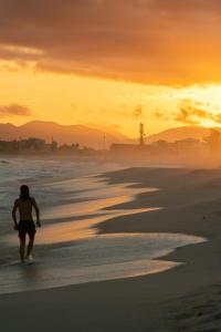 a person walking on the beach at sunset at Casa em Saquarema praia e verde in Saquarema +5 photos