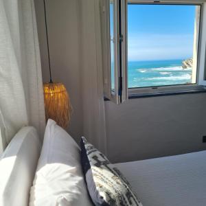 a bedroom with a bed and a window with the ocean at Casa das Marés 3 in Baleal