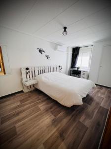 a bedroom with a large white bed and wooden floors at Casa Sempere in Elche