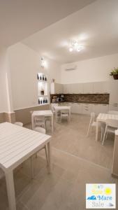 a room with white tables and chairs and a kitchen at Sole Mare Sale in Torre Nubia