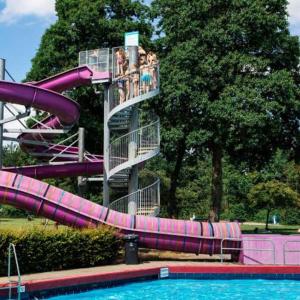 a purple water slide in a park with a pool at Luxury chalet Stay Smiley with hottub - Includes FREE pool access in Heinkensand