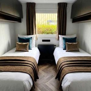 two beds in a room with a window at Luxury chalet Stay Smiley with hottub - Includes FREE pool access in Heinkensand +28 photos