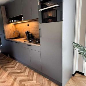 a kitchen with a white refrigerator and a wooden floor at Luxury chalet Stay Smiley with hottub - Includes FREE pool access in Heinkensand