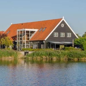 a large house next to a body of water at Luxury chalet Stay Smiley with hottub - Includes FREE pool access in Heinkensand