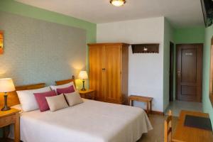 a bedroom with a bed with pink and white pillows at Hotel Capellan in Navia