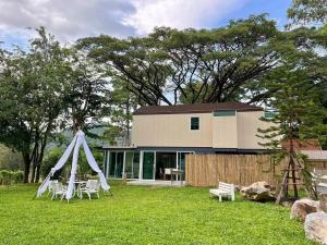 a house with a tent and chairs in a yard at Little Tree House in Mu Si