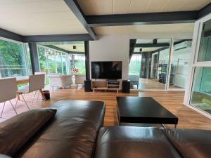 a living room with a leather couch and a television at Little Tree House in Mu Si