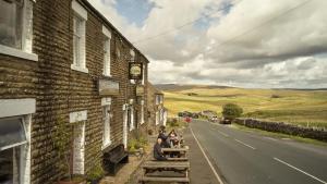 a group of people sitting on a bench outside of a building at The Station Inn - Ribblehead in Ribblehead Station