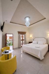 a bedroom with a white bed and a yellow chair at GRAN HOTEL VICTORIA in Rivas +29 photos