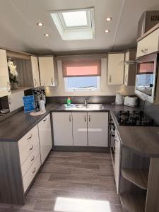 a large kitchen with white cabinets and a sink at Archerfield Luxe Lodge in Port Seton
