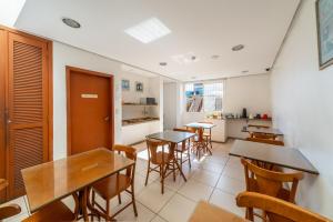 a dining room with tables and chairs and a kitchen at Minuano Hotel Home próximo ao aeroporto in Porto Alegre