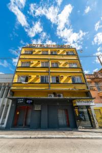 a yellow building with red doors on a street at Minuano Hotel Home próximo ao aeroporto in Porto Alegre
