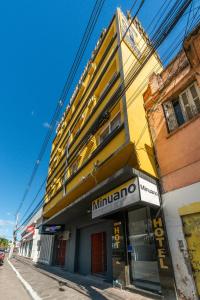 a yellow building with a minima store on a street at Minuano Hotel Home próximo ao aeroporto in Porto Alegre