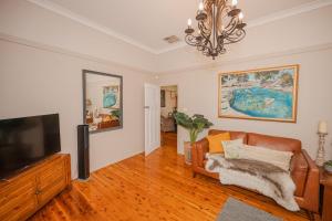 a living room with a couch and a flat screen tv at Cozy Cottage with Full Kitchen, Backyard & Patio in Tamworth