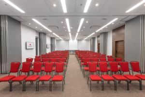 una sala conferenze con sedie rosse e schermo di Ramada by Wyndham Campinas Viracopos a Campinas