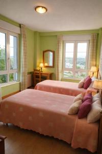 two beds in a room with two windows at Hotel Capellan in Navia