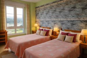 two beds in a hotel room with two windows at Hotel Capellan in Navia