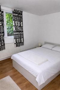 a white bed in a bedroom with black and white curtains at Canadian House in Sărata-Monteoru