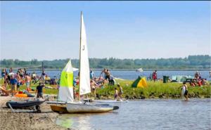 a group of people on a beach with sail boats at Ferienhaus Chalet Spaciosa Lauwersmeer in Lauwersoog