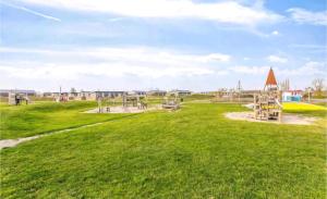 a playground with a slide in a green field at Ferienhaus Chalet Spaciosa Lauwersmeer in Lauwersoog