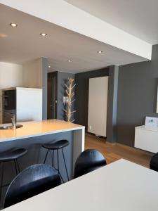 a kitchen with a counter and stools in a room at Zeezicht Rubensplein - 3slpk - gratis parking in Knokke-Heist +3 photos