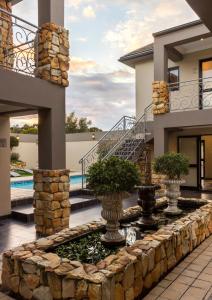 a house with a stone retaining wall and a fountain at Stone Olive in Jeffreys Bay